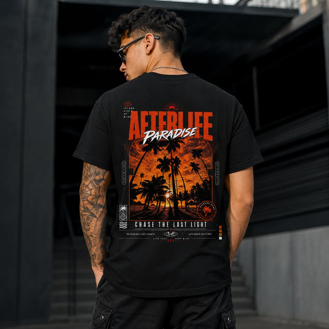 Schwarzes Unisex T-Shirt mit großem orange-weißem AFTERLIFE PARADISE Backprint, Palmen-Sonnenuntergang und Streetwear-Design an einem Zaun.